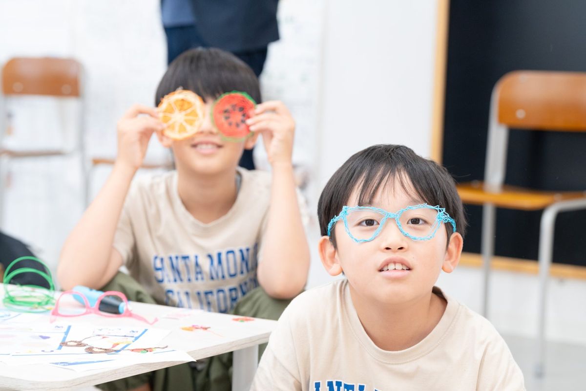 つくったメガネやフルーツの作品を、顔の前にかざして笑う子どもたち
